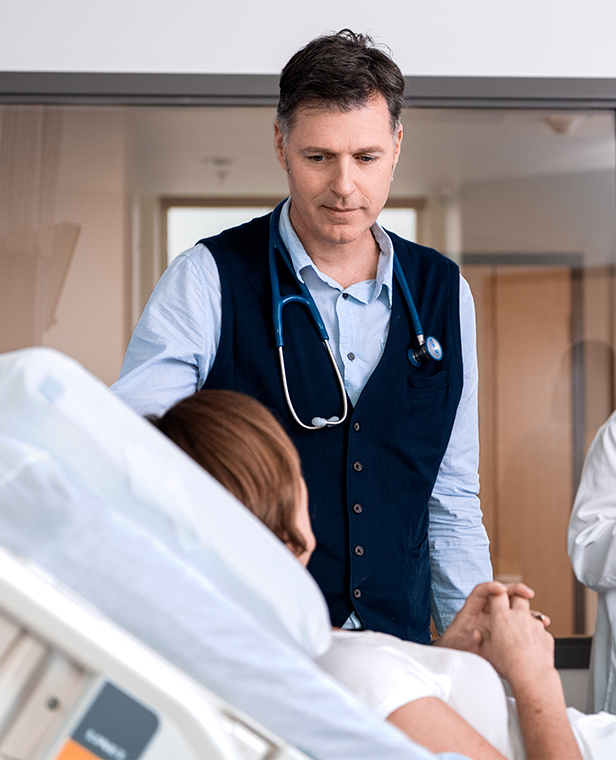 Un médecin discute avec une patiente allongée dans un lit d'hôpital.