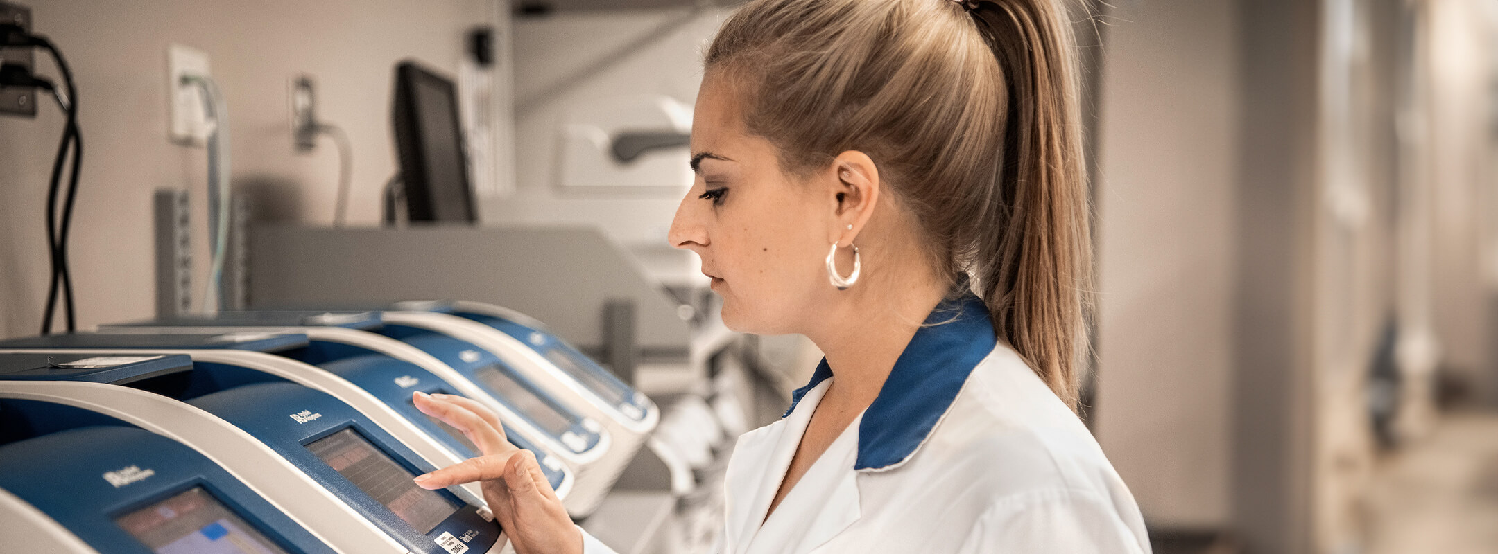 Une infirmière debout devant une rangée de machines.